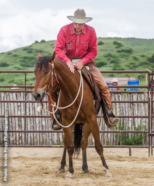 Buck astride his horse and pats horse's neck